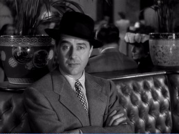 Movie still from “The Lost Weekend” (1945), directed by Billy Wilder – A black and white photo of a man in a suit and hat; Medium shot, Over the shoulder angle