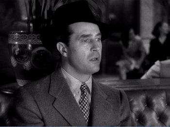 Movie still from “The Lost Weekend” (1945), directed by Billy Wilder – A black and white photo of a man wearing a suit and a hat; Close Up shot, Low angle