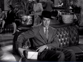 Movie still from “The Lost Weekend” (1945), directed by Billy Wilder – A black and white photo of a man sitting on a couch; Medium shot, High angle