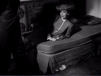Movie still from “The Lost Weekend” (1945), directed by Billy Wilder – A woman sitting on top of a bed wearing a hat; Medium shot, High angle