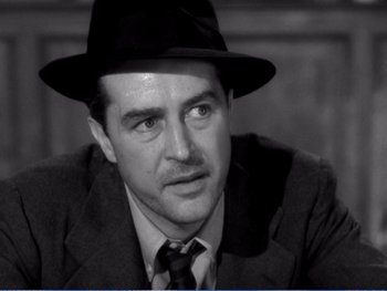 Movie still from “The Lost Weekend” (1945), directed by Billy Wilder – A black and white photo of a man wearing a suit and a hat; Close Up shot, Over the shoulder angle