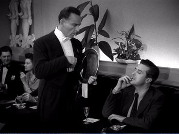 A man in a suit and tie holding a mirror in front of a man in a suit and tie