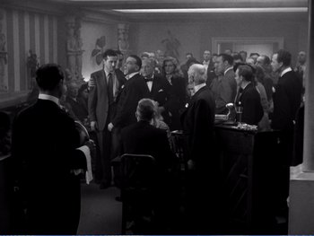 Movie still from “The Lost Weekend” (1945), directed by Billy Wilder – A group of men in suits and ties standing around a bar; Wide shot, High angle