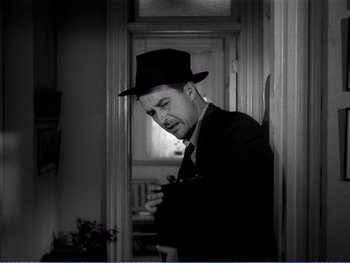 Movie still from “The Lost Weekend” (1945), directed by Billy Wilder – A black and white photo of a man in a suit and a hat; Medium shot, Low angle