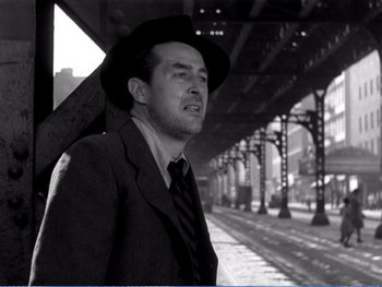 Movie still from “The Lost Weekend” (1945), directed by Billy Wilder – A black and white photo of a man in a suit and hat; Medium shot, Low angle