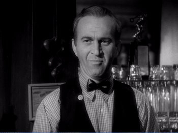 Movie still from “The Lost Weekend” (1945), directed by Billy Wilder – An older man wearing a bow tie in front of a bar; Close Up shot, Low angle