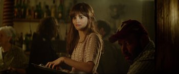 Movie still from “The Man Who Killed Don Quixote” (2018), directed by Terry Gilliam – A woman sitting in front of other people in a room; Medium shot, Over the shoulder angle