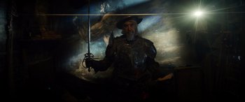 Movie still from “The Man Who Killed Don Quixote” (2018), directed by Terry Gilliam – A man dressed as a medieval knight holding a sword; Medium shot, Low angle