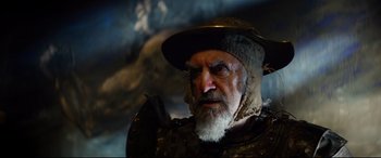 Movie still from “The Man Who Killed Don Quixote” (2018), directed by Terry Gilliam – An old man with a beard wearing a hat; Close Up shot, Over the shoulder angle