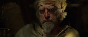 Movie still from “The Man Who Killed Don Quixote” (2018), directed by Terry Gilliam – An old man with a white beard wearing a yellow bandanna; Close Up shot, Over the shoulder angle