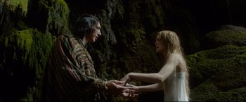 Movie still from “The Man Who Killed Don Quixote” (2018), directed by Terry Gilliam – A man and a woman holding hands in front of a rock wall; Medium shot, Overhead angle