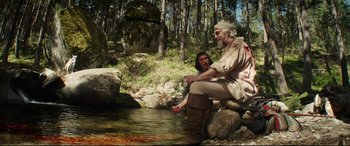 Movie still from “The Man Who Killed Don Quixote” (2018), directed by Terry Gilliam – A man sitting on a rock next to a man in the water; Wide shot, Over the shoulder angle