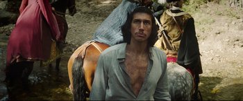 Movie still from “The Man Who Killed Don Quixote” (2018), directed by Terry Gilliam – A man with long black hair stands next to a horse; Medium shot, High angle
