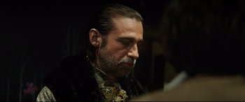 Movie still from “The Man Who Killed Don Quixote” (2018), directed by Terry Gilliam – A person wearing a suit and tie; Close Up shot, Over the shoulder angle