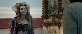 Movie still from “The Man Who Killed Don Quixote” (2018), directed by Terry Gilliam – A woman in a medieval dress standing in front of a building; Close Up shot, Over the shoulder angle