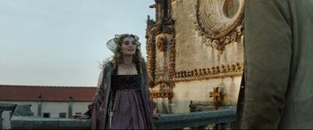 Movie still from “The Man Who Killed Don Quixote” (2018), directed by Terry Gilliam – A woman dressed in medieval clothing stands in front of a building; Medium shot, Low angle