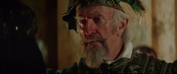 Movie still from “The Man Who Killed Don Quixote” (2018), directed by Terry Gilliam – An old man with a long beard wearing a hat; Close Up shot, Over the shoulder angle
