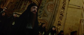 Movie still from “The Man Who Killed Don Quixote” (2018), directed by Terry Gilliam – A man with long hair and a beard wearing a black robe; Medium shot, Low angle