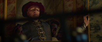Movie still from “The Man Who Killed Don Quixote” (2018), directed by Terry Gilliam – A man wearing a red hat is sitting in a dark room; Medium shot, Over the shoulder angle