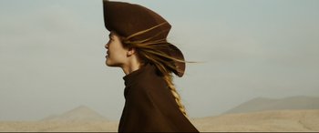 Movie still from “The Man Who Killed Don Quixote” (2018), directed by Terry Gilliam – A woman with a hat and a long braid in the desert; Close Up shot, Low angle