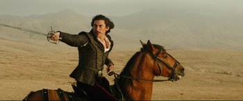Movie still from “The Man Who Killed Don Quixote” (2018), directed by Terry Gilliam – A man riding on the back of a brown horse; Medium shot, Low angle