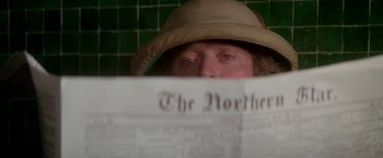 Movie still from “The Man Who Would Be King” (1975), directed by John Huston – A man in a hat is reading a newspaper; Close Up shot, Over the shoulder angle