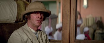 Movie still from “The Man Who Would Be King” (1975), directed by John Huston – A man wearing a hat sitting in front of a mirror; Close Up shot, Over the shoulder angle