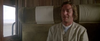 Movie still from “The Man Who Would Be King” (1975), directed by John Huston – A man wearing a white coat and a white shirt; Close Up shot, Over the shoulder angle