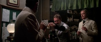 Movie still from “The Man Who Would Be King” (1975), directed by John Huston – A man holding a glass of wine in front of another man; Medium shot, Over the shoulder angle
