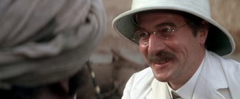 Movie still from “The Man Who Would Be King” (1975), directed by John Huston – An older man wearing a white hat and glasses; Close Up shot, Over the shoulder angle
