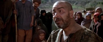 Movie still from “The Man Who Would Be King” (1975), directed by John Huston – An old man with a beard and a beard is looking at a crowd; Close Up shot, Over the shoulder angle