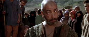 Movie still from “The Man Who Would Be King” (1975), directed by John Huston – An old man with a beard and a mustache is looking at the camera; Close Up shot, Over the shoulder angle