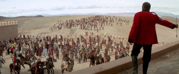 Movie still from “The Man Who Would Be King” (1975), directed by John Huston – A large group of people are gathered together in a field; Extreme Wide shot, High angle