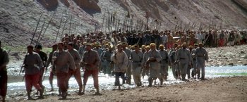 Movie still from “The Man Who Would Be King” (1975), directed by John Huston – A large group of people in the middle of the desert; Extreme Wide shot, High angle