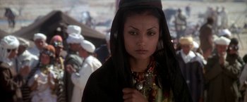 Movie still from “The Man Who Would Be King” (1975), directed by John Huston – A woman with a black headscarf and a necklace; Close Up shot, Over the shoulder angle