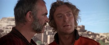 Movie still from “The Man Who Would Be King” (1975), directed by John Huston – Two men talking to each other in front of a building; Close Up shot, Low angle