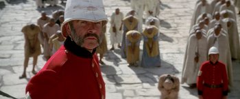 Movie still from “The Man Who Would Be King” (1975), directed by John Huston – A man in a red coat and a white hat; Close Up shot, Low angle