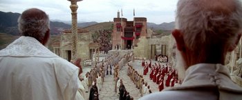 Movie still from “The Man Who Would Be King” (1975), directed by John Huston – A crowd of people are gathered in front of a building; Extreme Wide shot, High angle