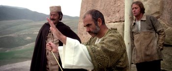 Movie still from “The Man Who Would Be King” (1975), directed by John Huston – A man in a robe holding a stick in front of another man in a robe; Medium shot, Over the shoulder angle