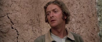 Movie still from “The Man Who Would Be King” (1975), directed by John Huston – A person wearing a shirt and jacket; Close Up shot, Over the shoulder angle