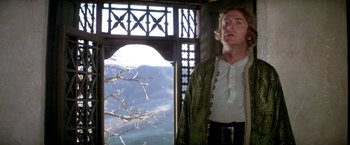 Movie still from “The Man Who Would Be King” (1975), directed by John Huston – A man standing in front of a window looking out; Medium shot, Low angle