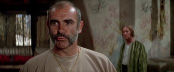 Movie still from “The Man Who Would Be King” (1975), directed by John Huston – A man with a beard is wearing a necklace; Close Up shot, Low angle