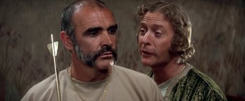 Movie still from “The Man Who Would Be King” (1975), directed by John Huston – A man and a woman standing next to each other; Close Up shot, Low angle