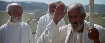 Movie still from “The Man Who Would Be King” (1975), directed by John Huston – A group of men standing next to each other on top of a hill; Medium shot, Low angle