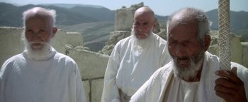 Movie still from “The Man Who Would Be King” (1975), directed by John Huston – A man with a long beard standing next to another man with a long beard; Medium shot, Low angle