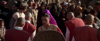 Movie still from “The Man Who Would Be King” (1975), directed by John Huston – A group of people standing in a crowd of men and women; Medium shot, Over the shoulder angle