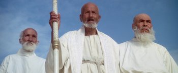 Movie still from “The Man Who Would Be King” (1975), directed by John Huston – An old man with a beard holding a white pole; Medium shot, Low angle