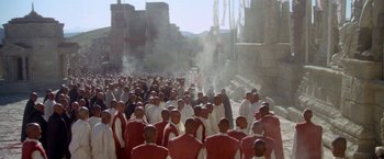 Movie still from “The Man Who Would Be King” (1975), directed by John Huston – A group of men in white and red robes standing next to each other on a street; Extreme Wide shot, High angle
