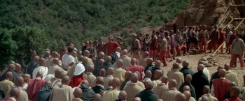Movie still from “The Man Who Would Be King” (1975), directed by John Huston – A large group of people gathered on a hillside; Extreme Wide shot, High angle