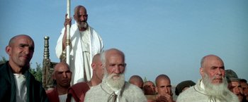 Movie still from “The Man Who Would Be King” (1975), directed by John Huston – A group of bald men standing next to each other; Medium shot, Low angle